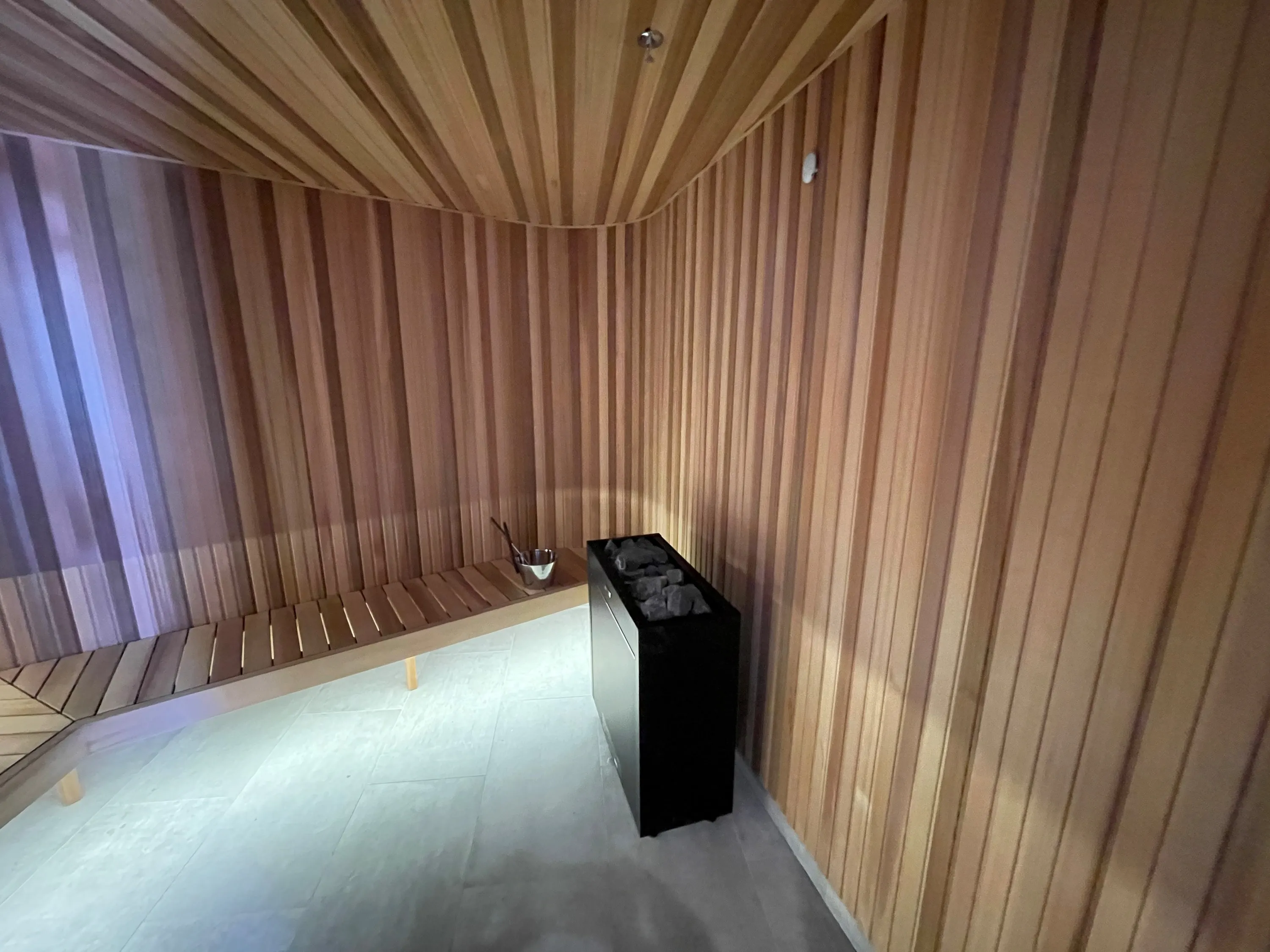 Timber ceiling boards meeting vertical timber walls above a sauna heater