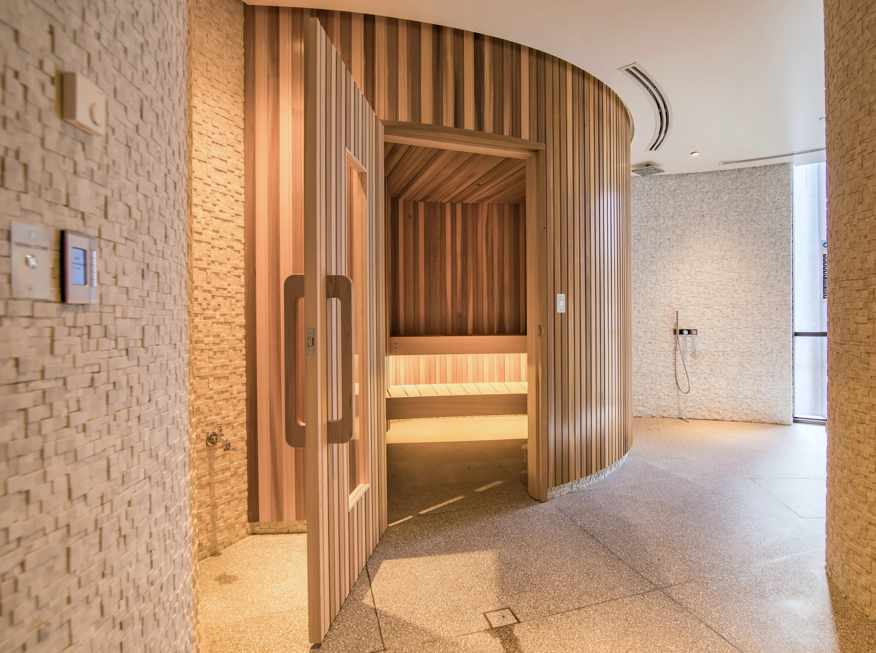 Cedar sauna door open onto lit tiered benches