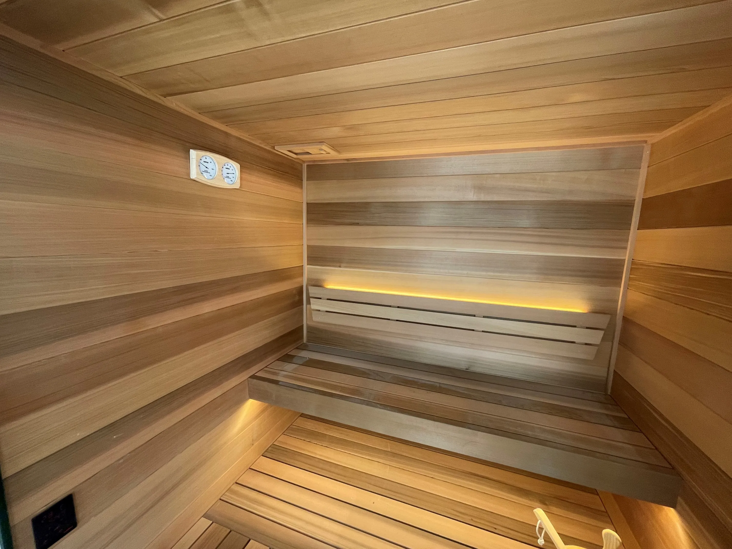 Horizontal timber sauna with lit backrests above two tiers of benches