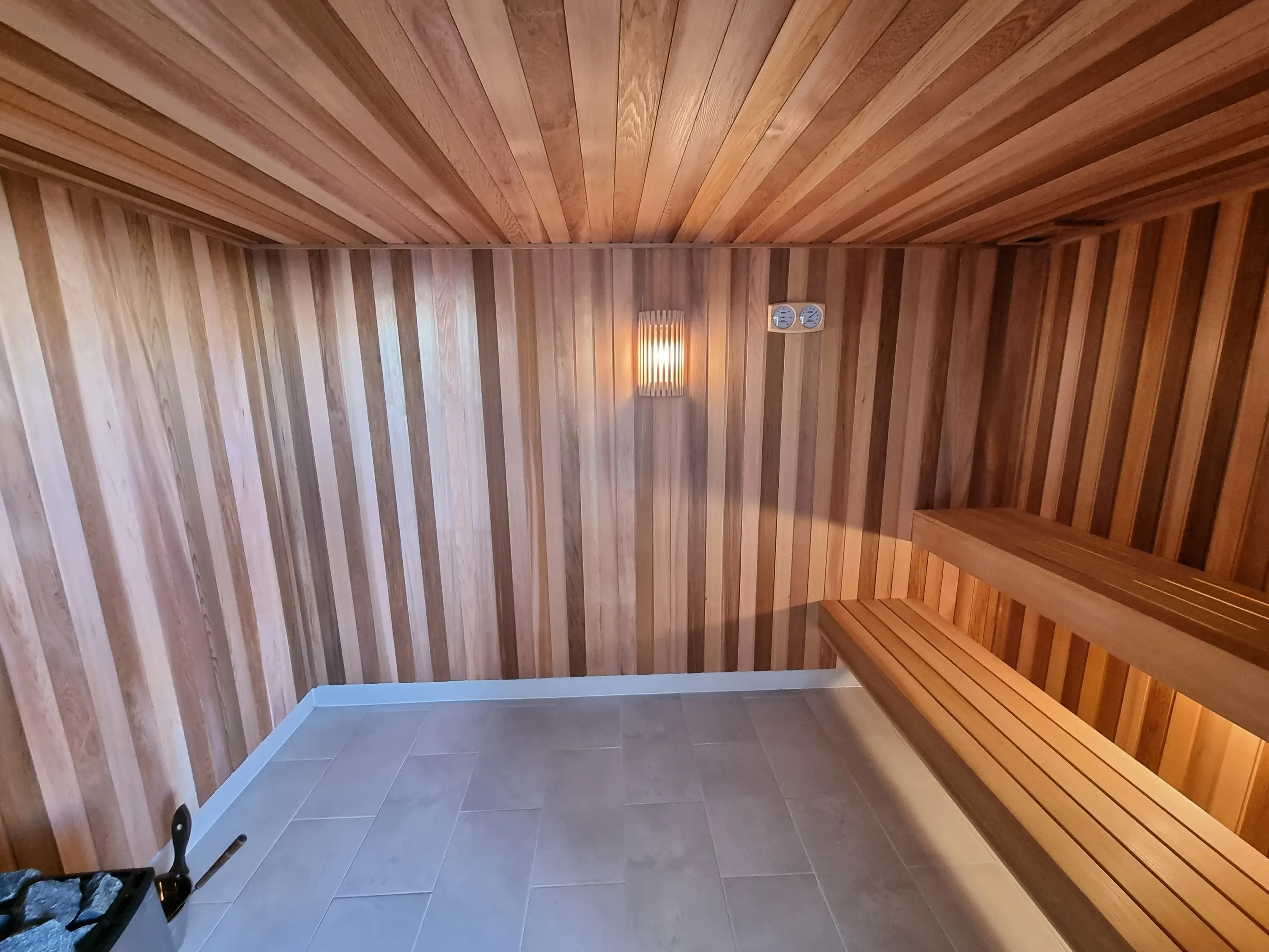 Timber sauna with a long bench and a wall light