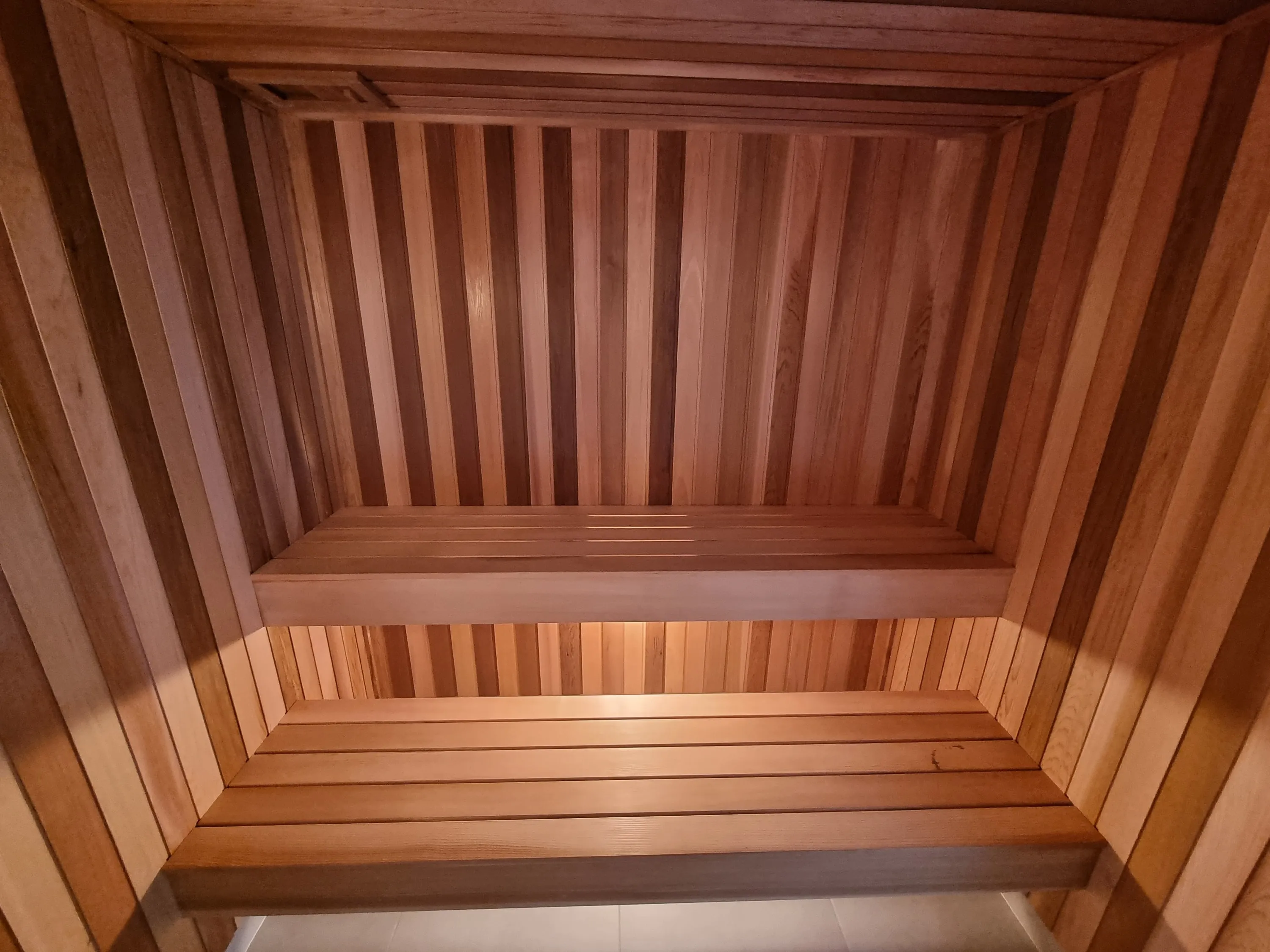 Timber sauna with two tiers of benches beneath a timber ceiling