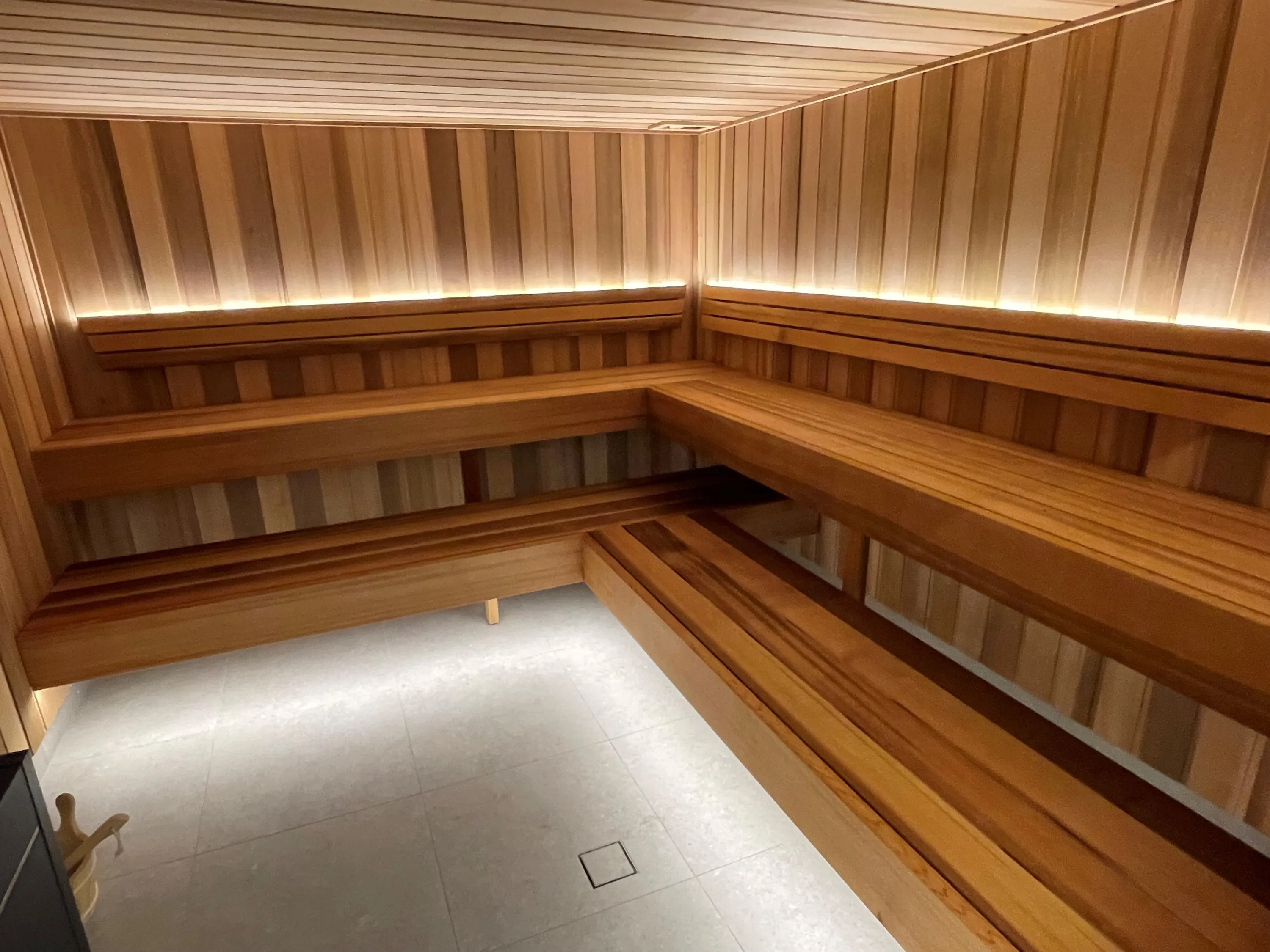 Commercial sauna with long tiered timber benches and concealed lighting