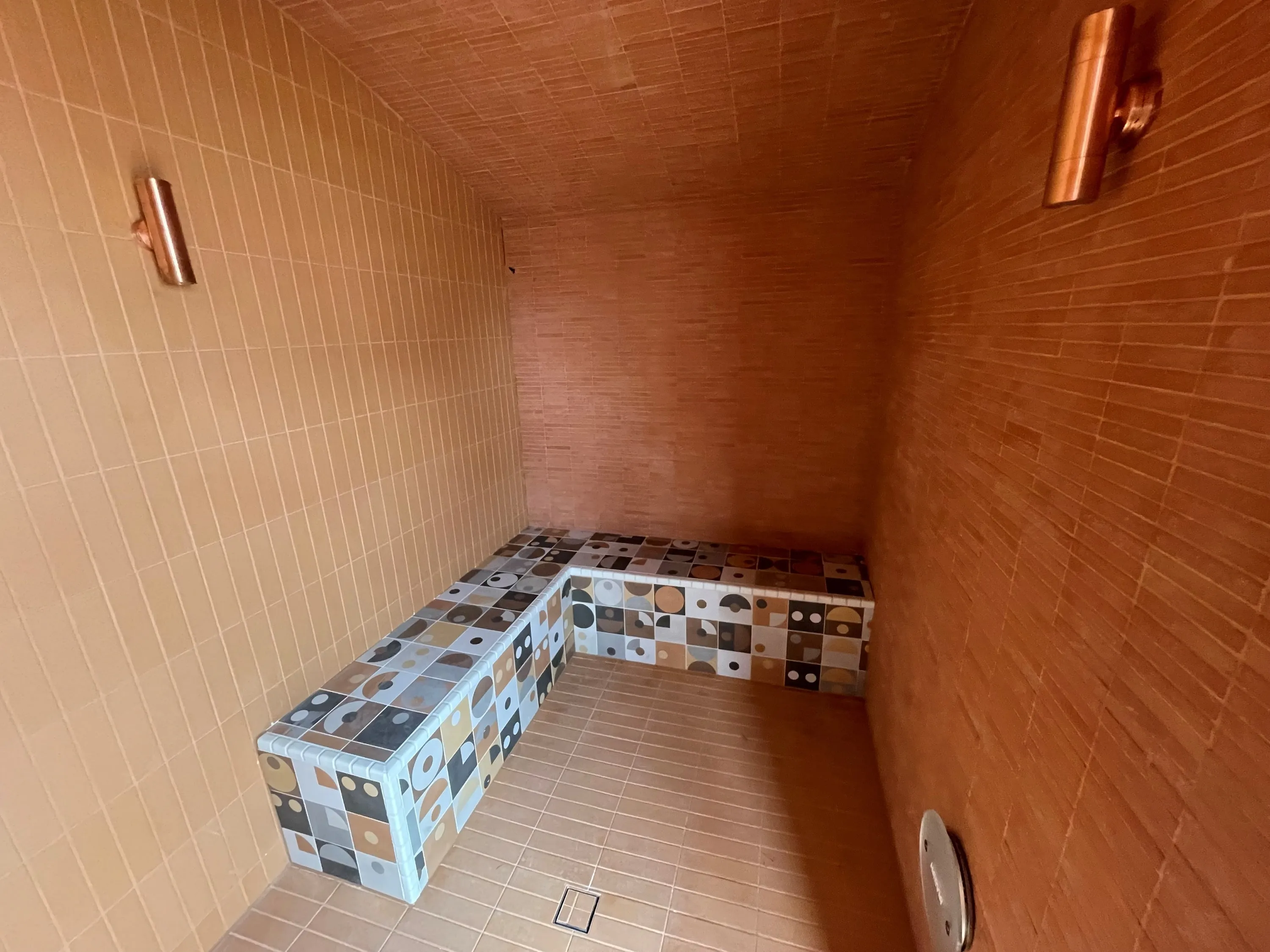 Tiled commercial steam room with an L-shaped patterned bench