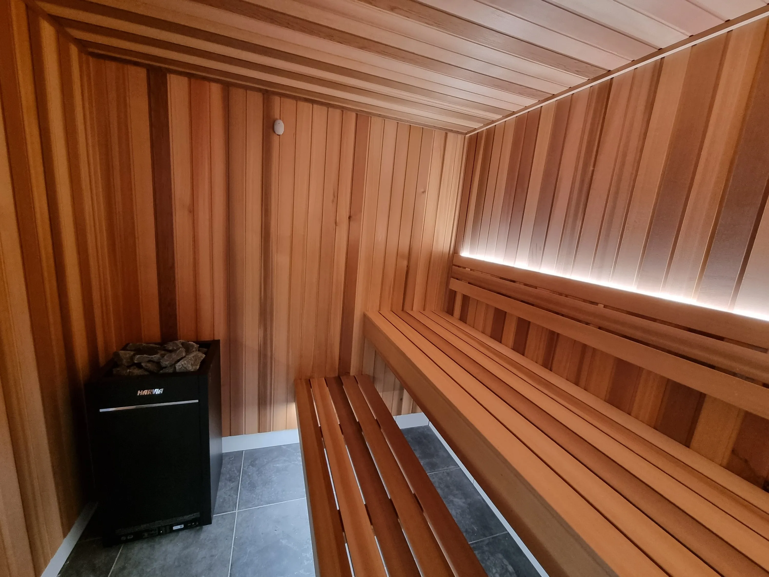 Black sauna heater beside a two-tier timber bench