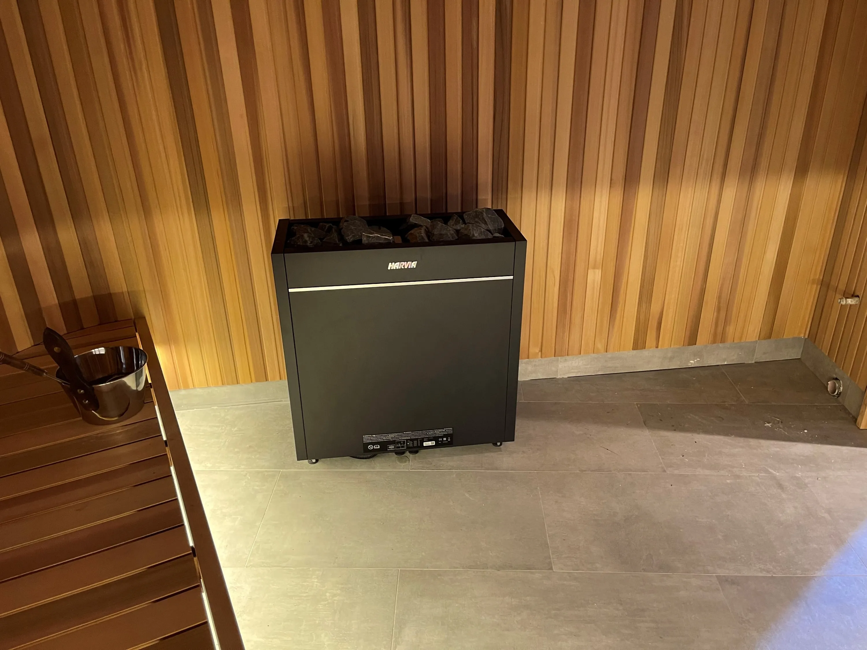 Black heater filled with stones against vertical timber boards