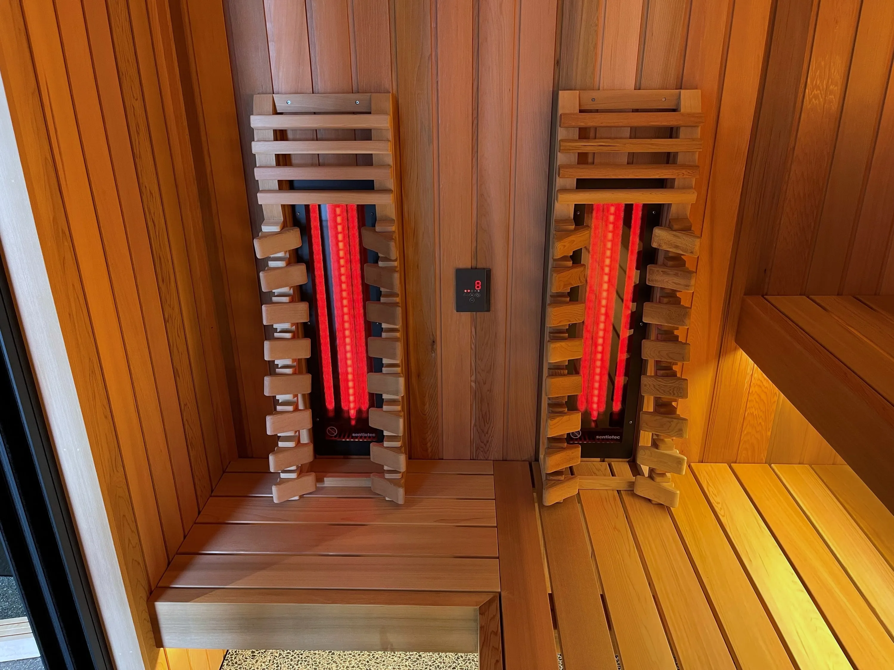 Pair of vertical infrared emitters behind slatted timber guards above a sauna bench