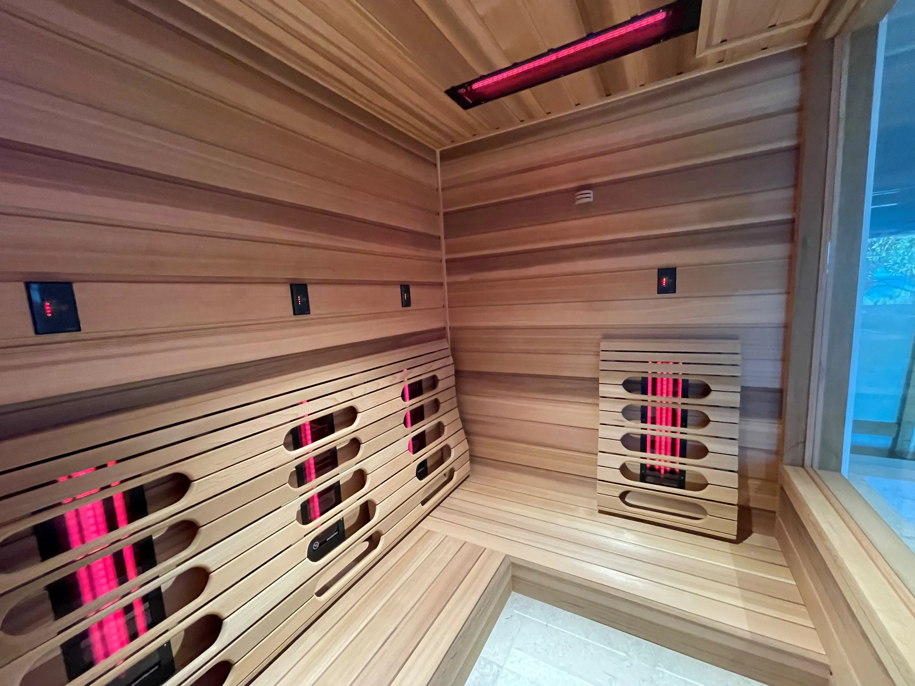 Timber infrared sauna with emitter panels on two walls and a ceiling emitter