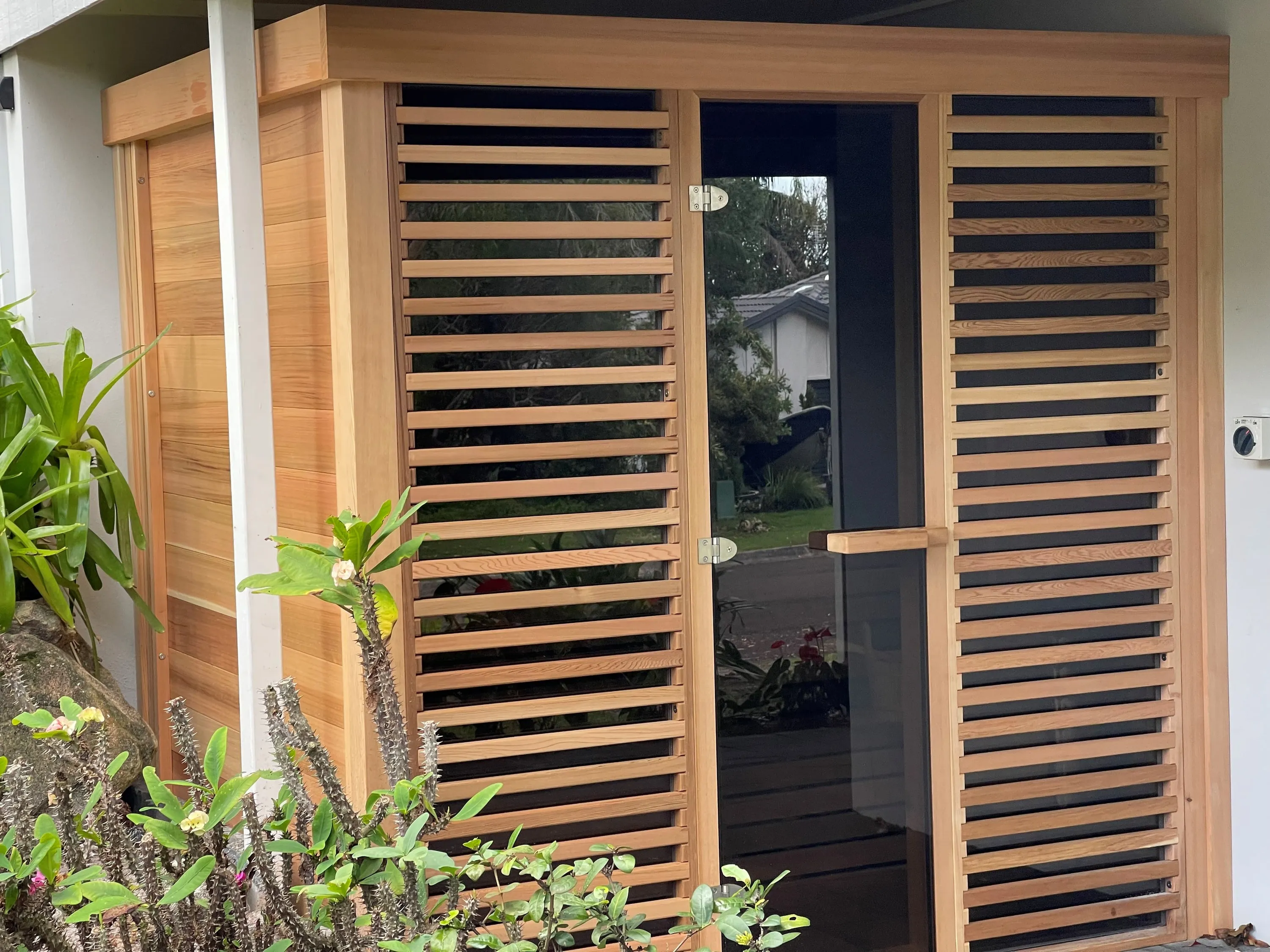 Cedar Pure Cube sauna with louvred panels either side of a glass door