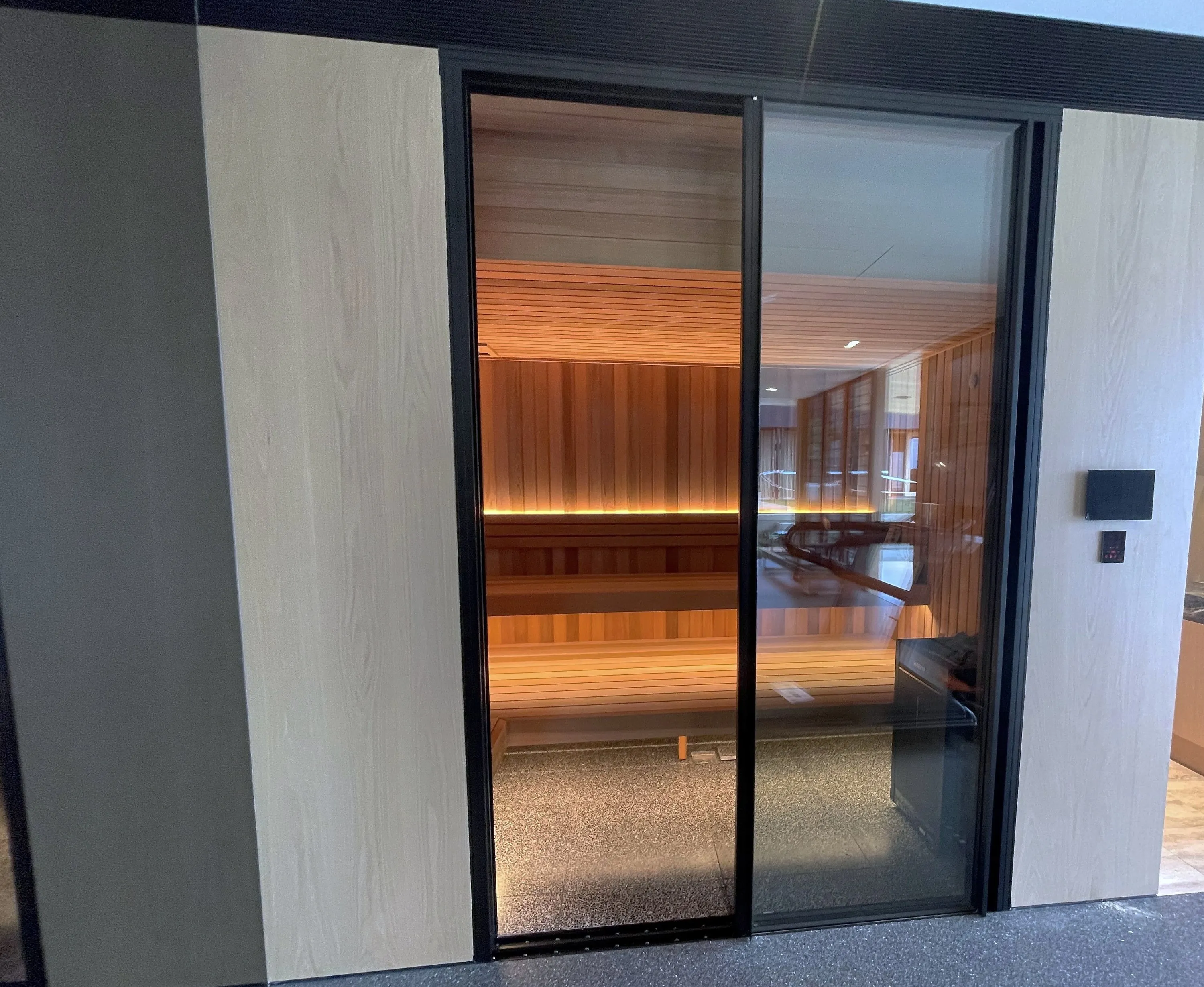 Glass sliding doors opening onto a warmly lit timber home sauna