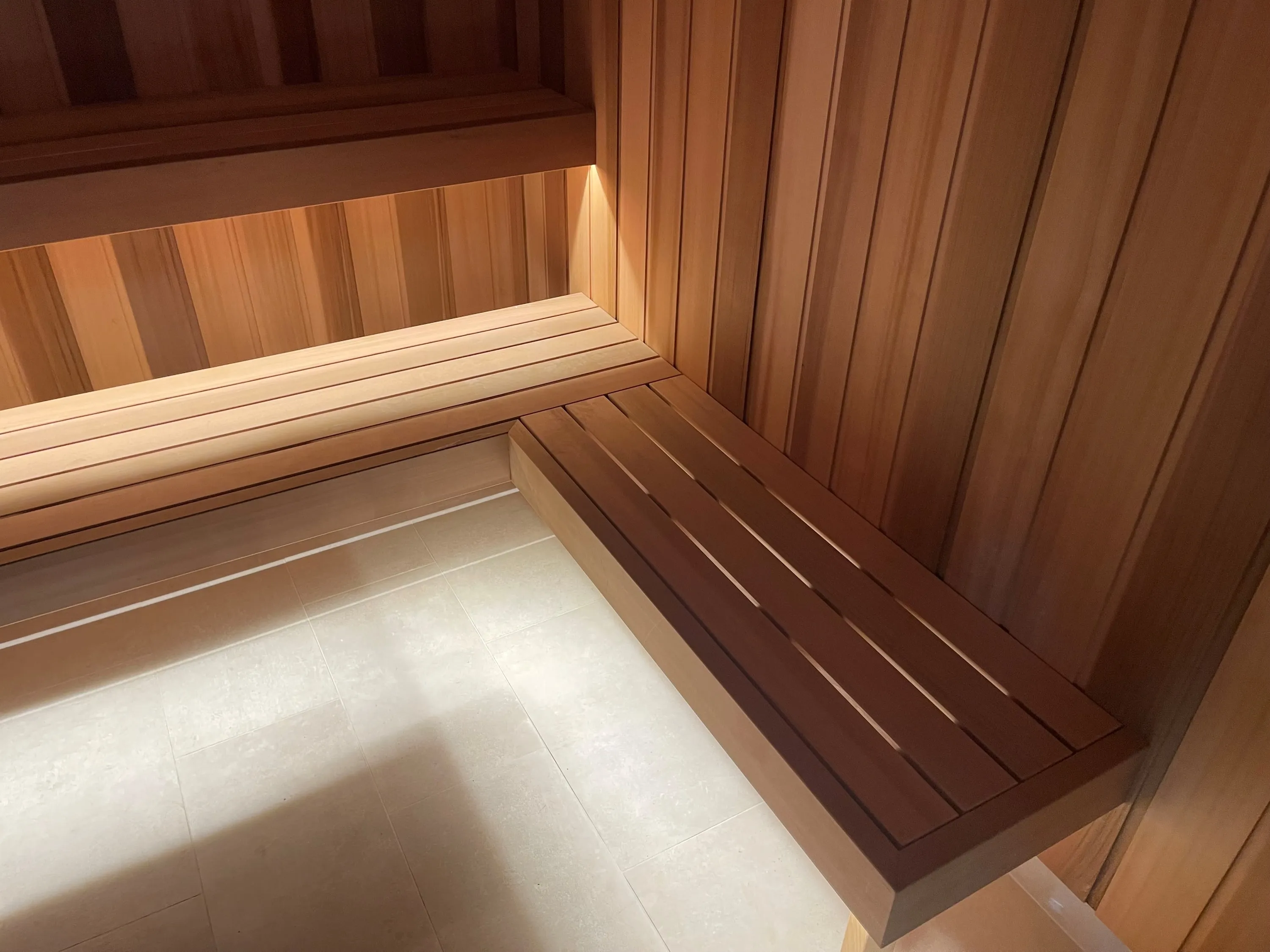 Corner of a two-tier sauna bench with soft lighting beneath the upper bench
