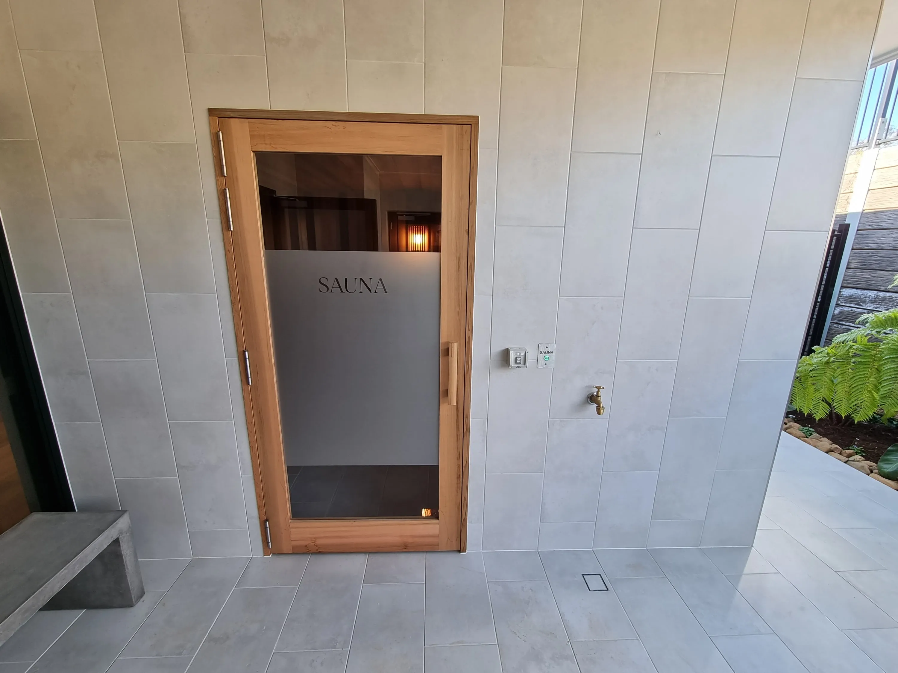 Timber-framed glass sauna door set into a tiled wall