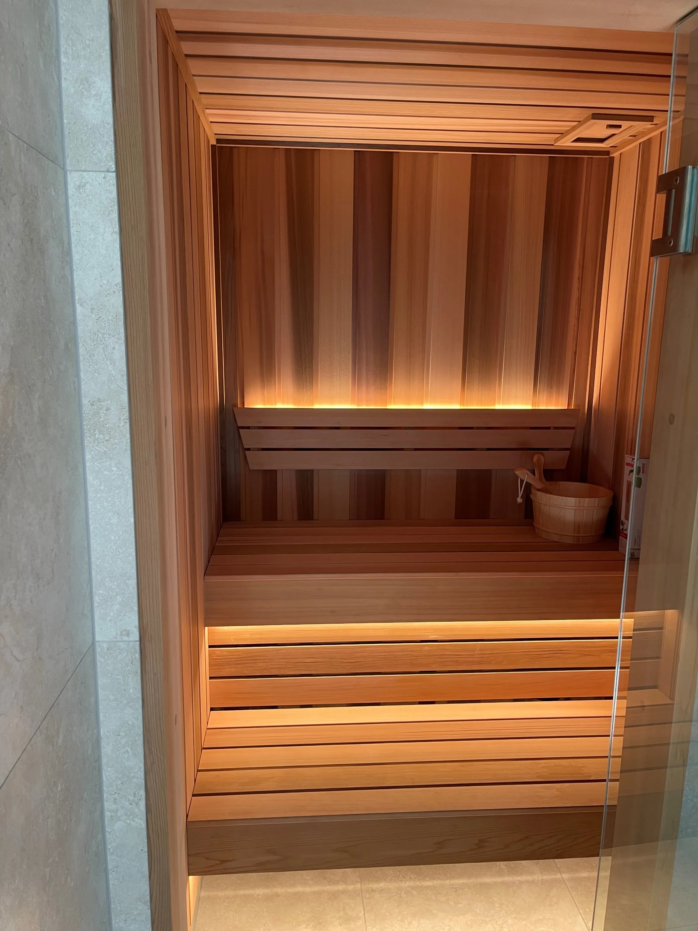 Timber sauna with softly lit backrest and benches seen through the open door