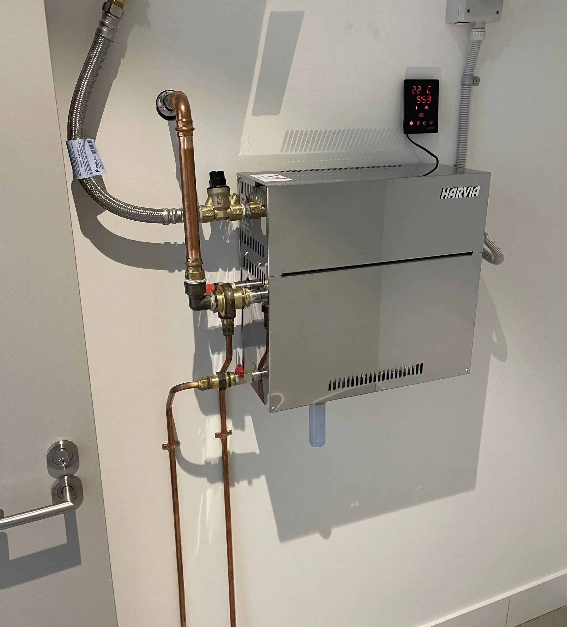 Wall-mounted steam generator with copper water and steam connections in a plant room