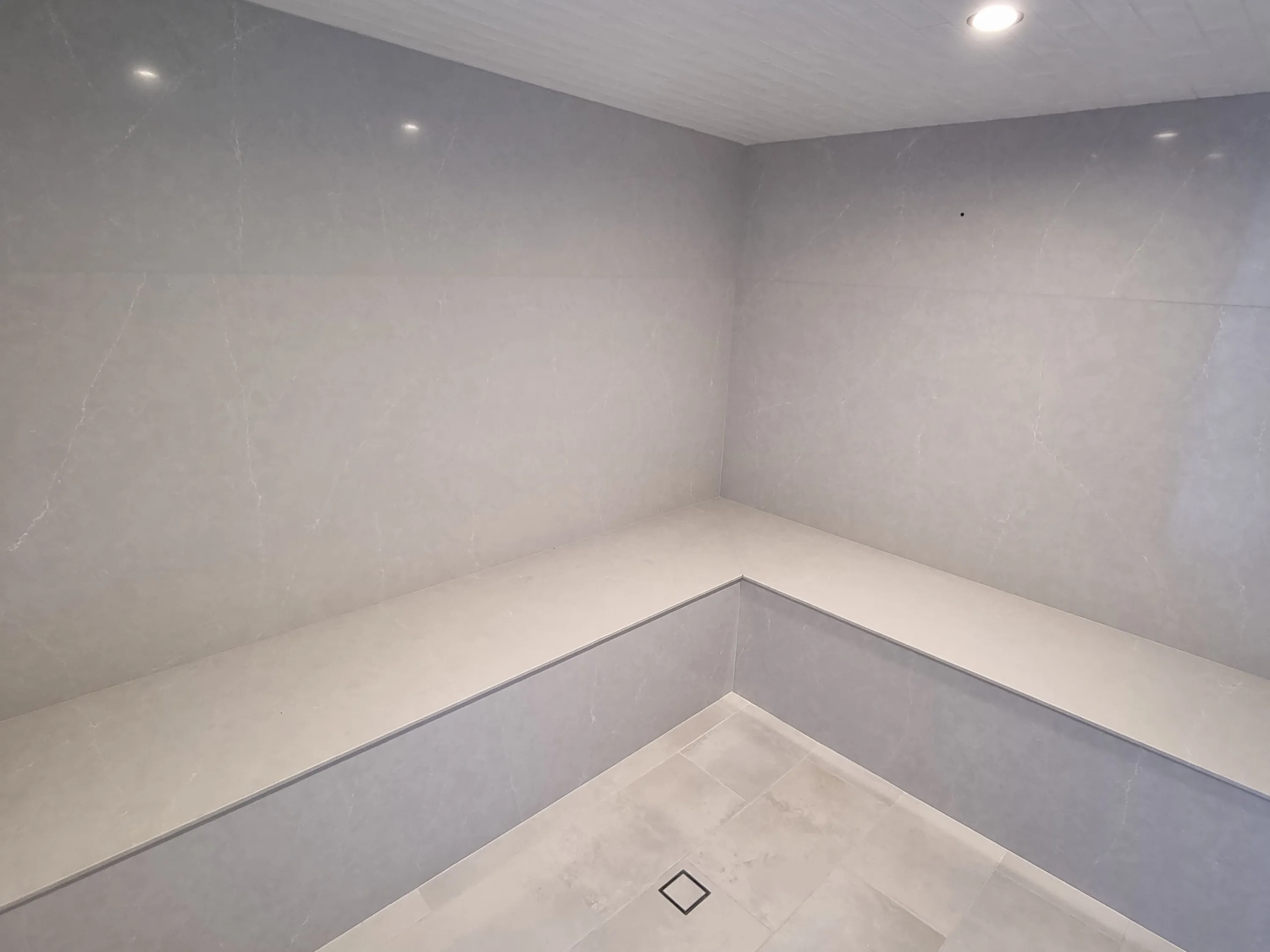Fully tiled steam room with a continuous tiled bench and floor drain