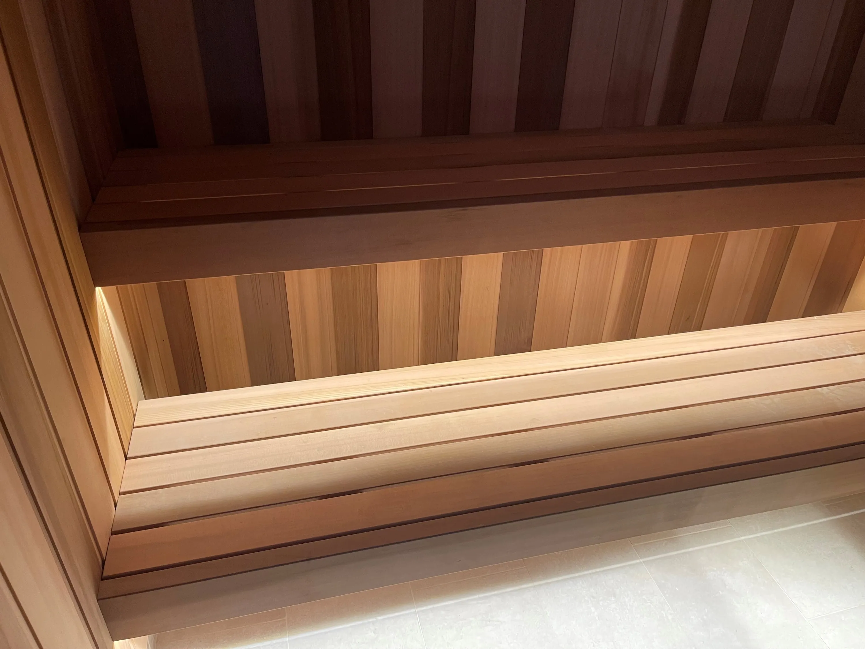 Two-tier sauna benches with softly lit timber lining