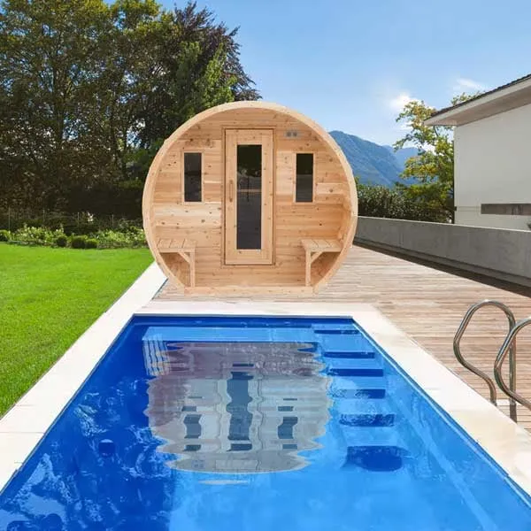 Front of a light cedar barrel sauna with porch benches, glass-panel door and two windows, on a timber deck beside a swimming pool and lawn (composited scene).