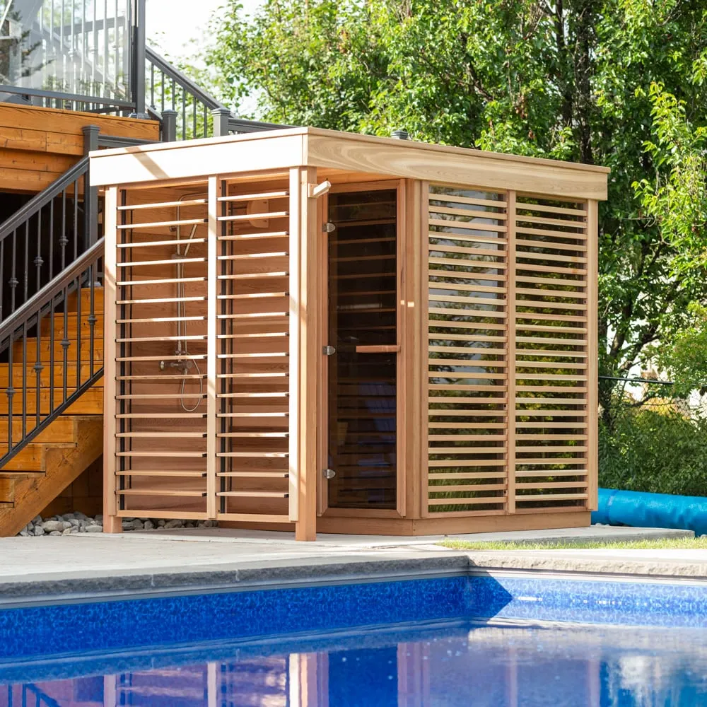 Flat-roof clear cedar outdoor cube sauna with horizontal louvre screens, glass door and covered shower bay, beside a pool and deck stairs